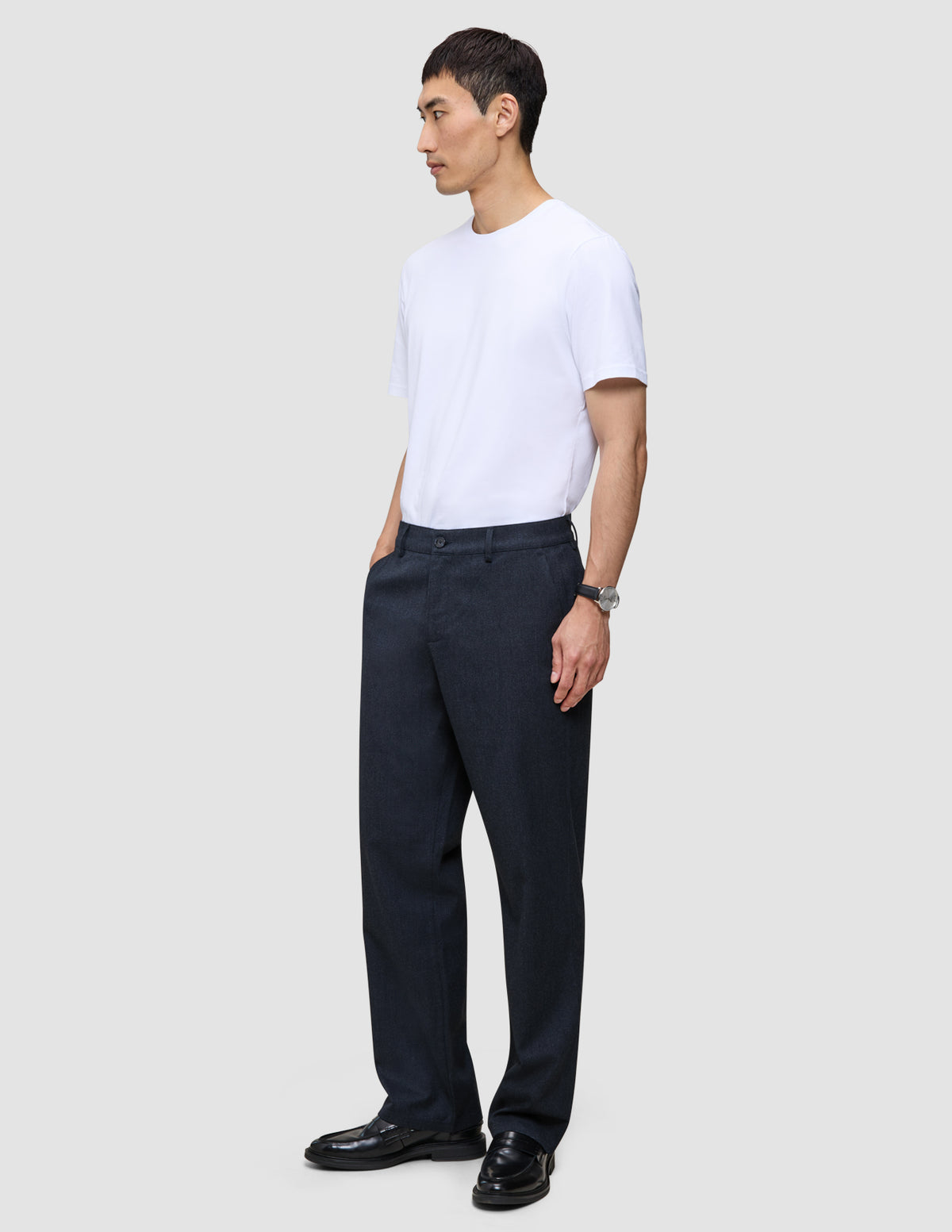 En mand i en hvid T-shirt og Atelier Pants Relaxed Dark Navy, stylet i minimalistisk dansk design.