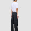 En mand set bagfra, iført en hvid T-shirt og et par Atelier Pants Relaxed i mørk marineblå.