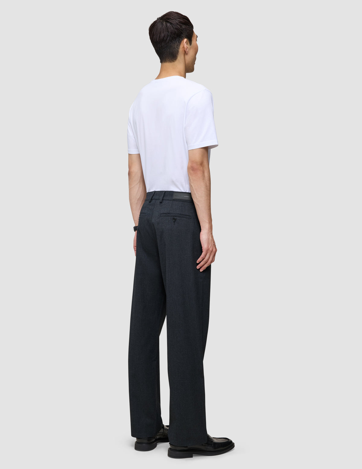 En mand set bagfra, iført en hvid T-shirt og et par Atelier Pants Relaxed i mørk marineblå.