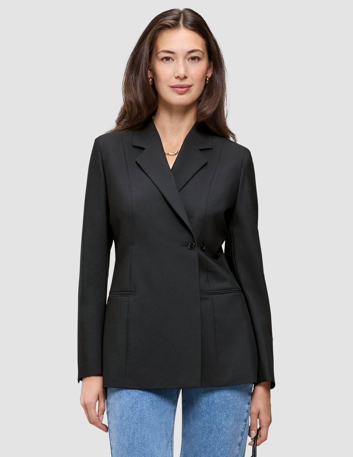En kvinde iført en sort Avira-blazer til kvinder over lyseblå jeans i dansk design-stil.