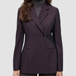 En person iført en Avira-blazer i farven Burgundy Berry til kvinder over en grå rullekravesweater, der afspejler klassisk dansk design.