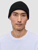 En person, der bærer en håndstrikket Beanie Black i ribstrikket sort merinould.