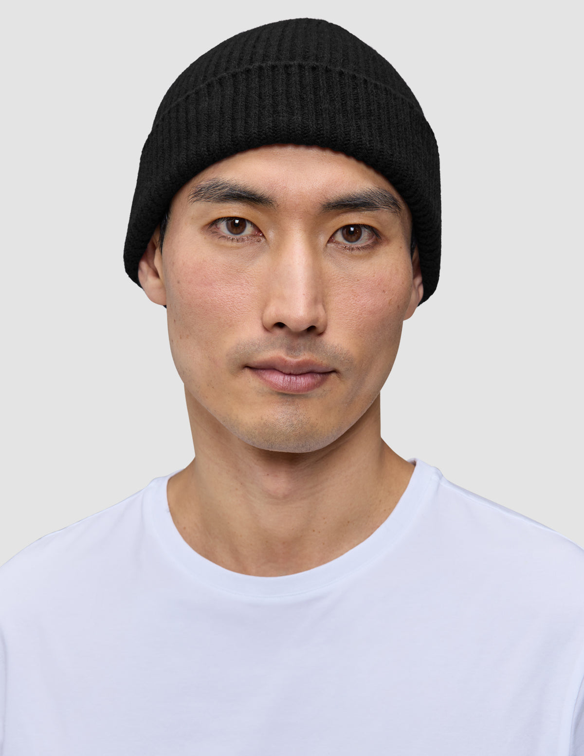 En person, der bærer en håndstrikket Beanie Black i ribstrikket sort merinould.