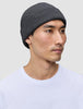 En person, der bærer en mørkegrå Beanie Dark Grey, en ribstrikket hue i merinould i dansk design.