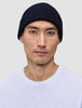 En mand iført en ribstrikket, marineblå Wool Beanie Navy-hue i merinould.