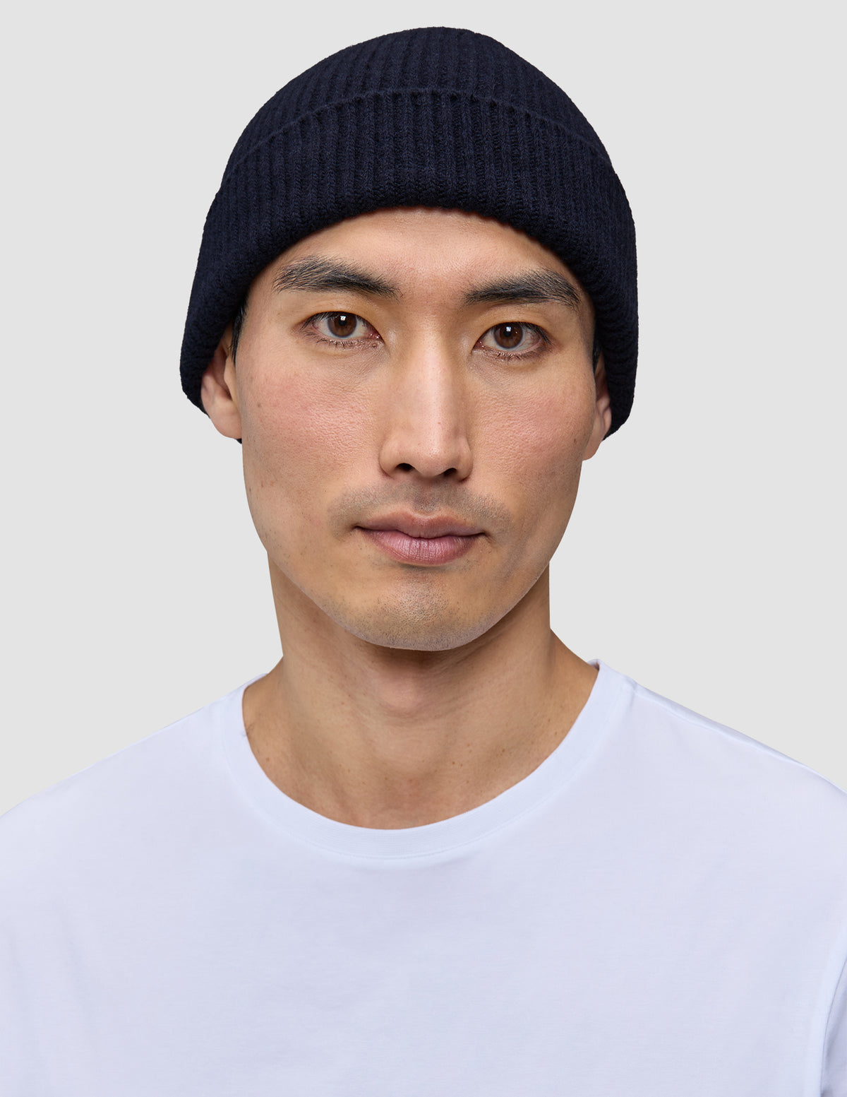 En mand iført en ribstrikket, marineblå Wool Beanie Navy-hue i merinould.