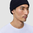 En mand iført en marineblå, håndstrikket merinould-hue af mærket Wool Beanie Navy i dansk design.