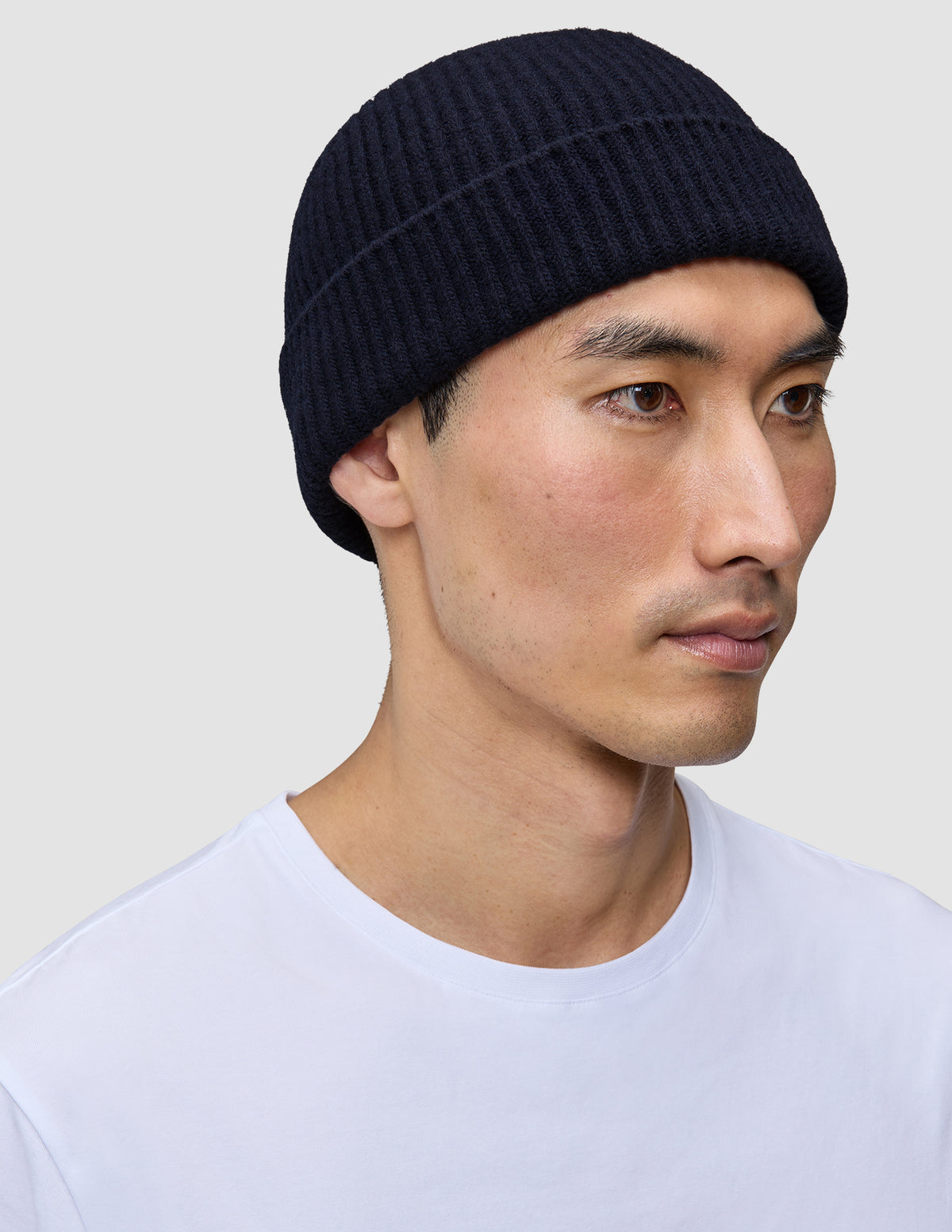 En mand iført en marineblå, håndstrikket merinould-hue af mærket Wool Beanie Navy i dansk design.