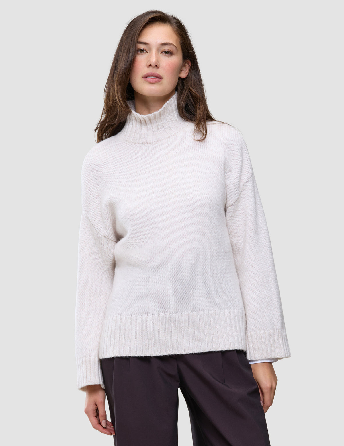 En kvinde iført en Women’s Chunky Soft Wool Knit Turtleneck Sugar Melange-trøje med høj hals i grovstrik.