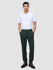 En mand iført en hvid T-shirt og mørkegrønne Ease Pants Regular Northern Pine med hænderne i lommerne.