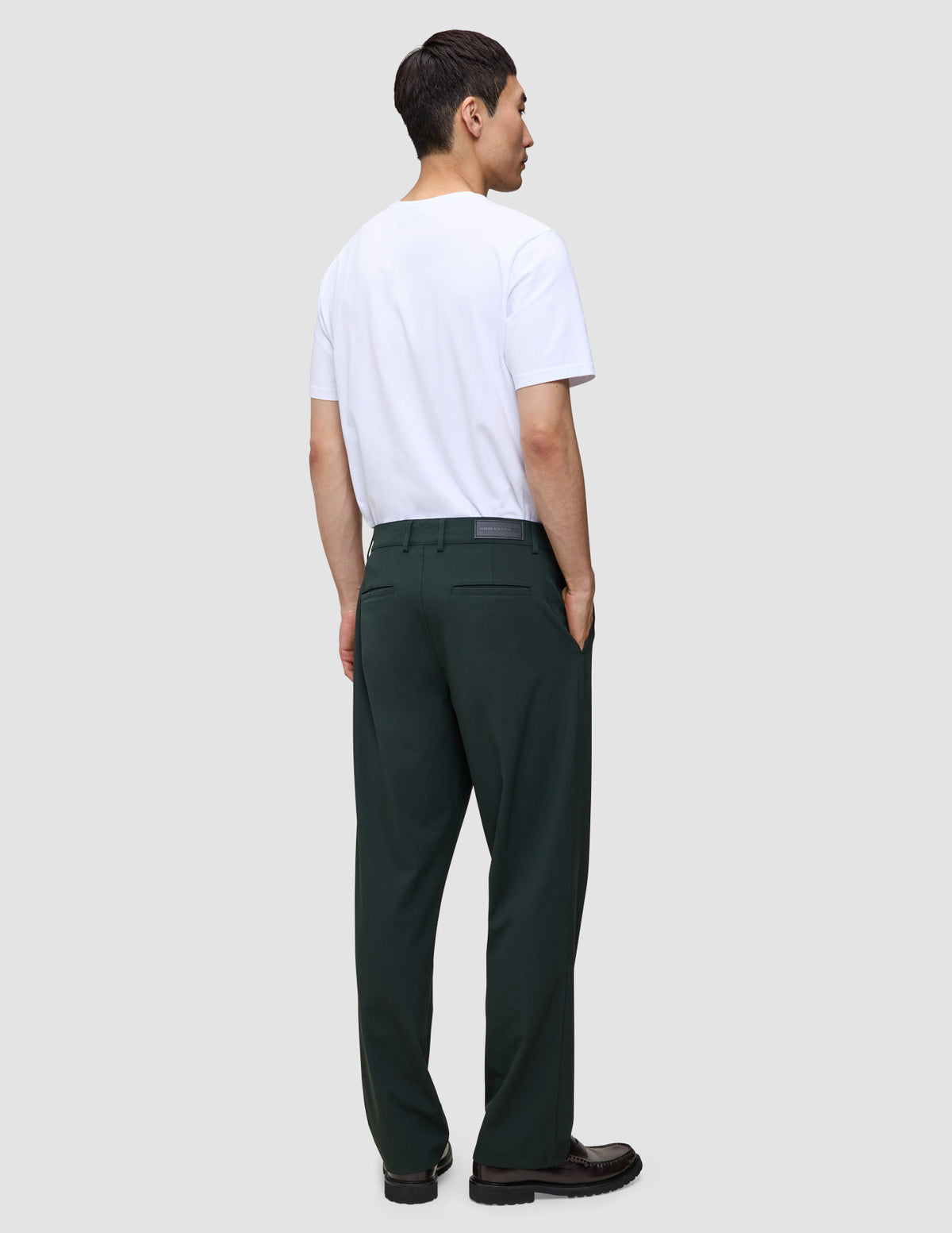 En mand set bagfra, iført en hvid T-shirt og mørkegrønne Ease Pants Relaxed Fit Northern Pine i en afslappet pasform.