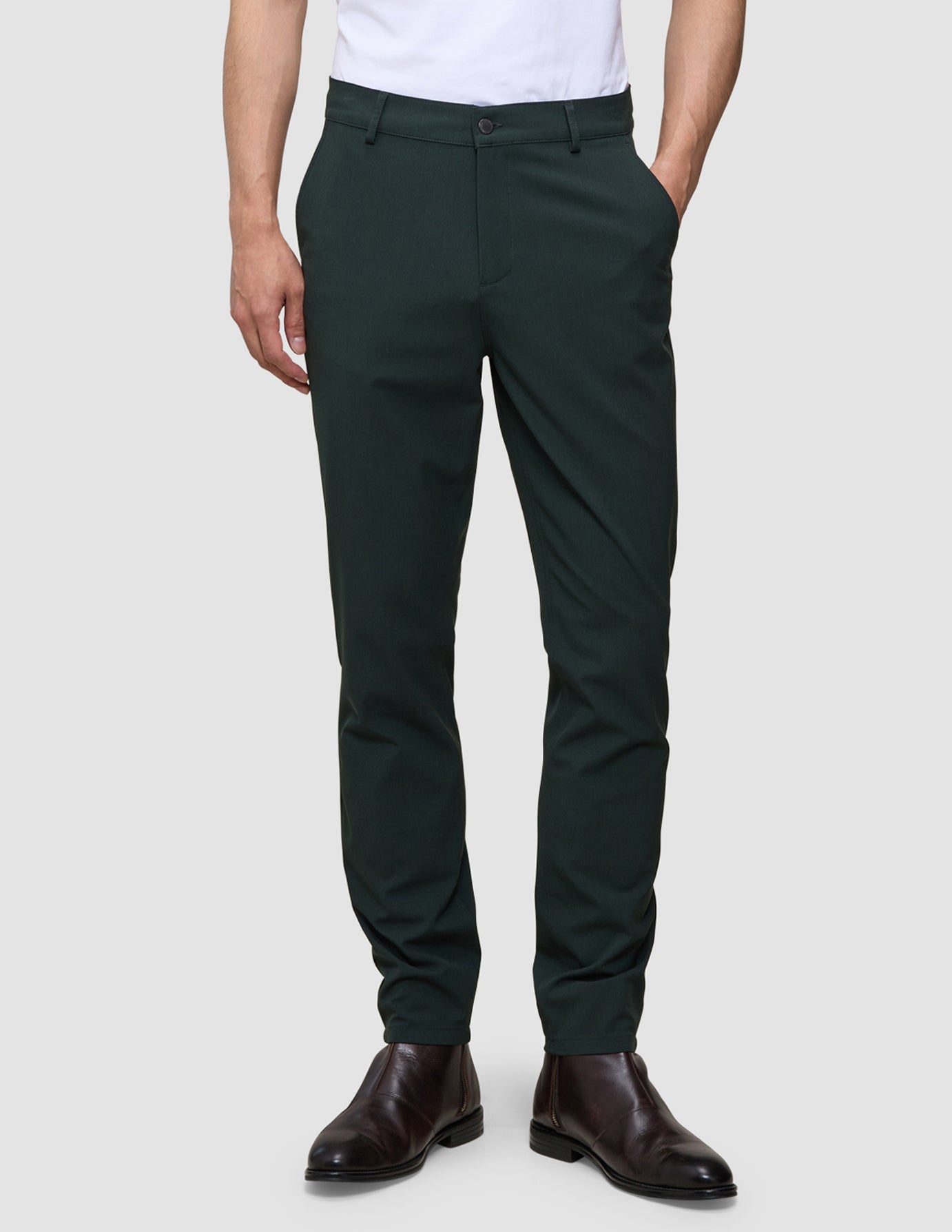 En person iført Ease Pants Slim Northern Pine med 360°-stretch og brune læderstøvler.