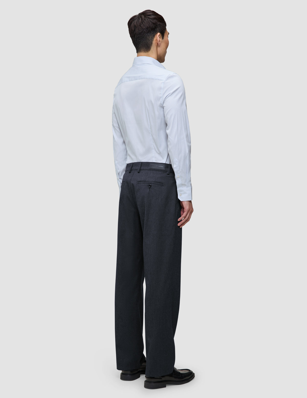 En mand set bagfra iført en Elevated Shirt Regular Classic Blue Striped, antracitgrå bukser og sorte loafers.
