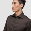 En mand iført en mørkebrun Elevated Shirt Regular-skjorte med knapper.