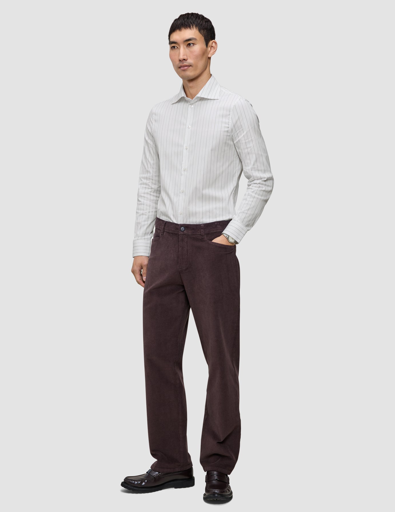 En mand iført en Elevated Shirt Regular Light Grey Striped, mørke bukser og mørke loafers.