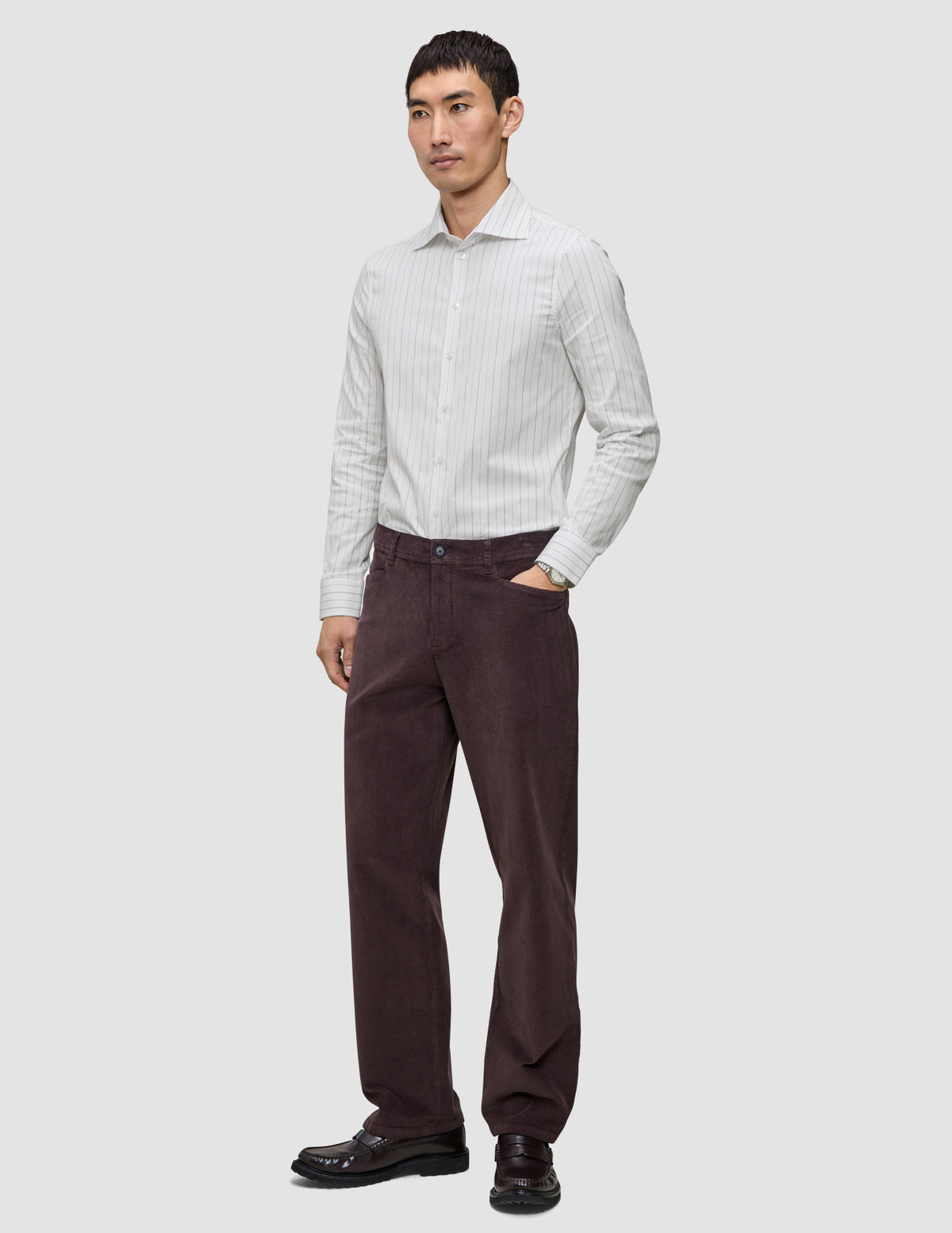 En mand iført en Elevated Shirt Regular Light Grey Striped, mørke bukser og mørke loafers.