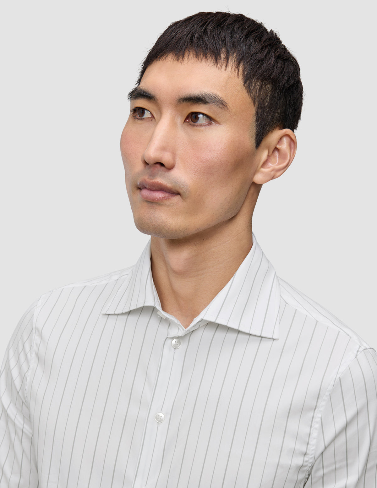 En mand iført en Elevated Shirt Regular Light Grey Striped, en hvid skjorte med tynde grå lodrette striber.