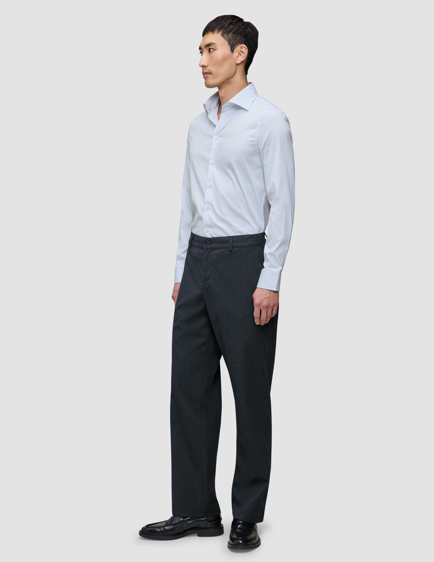 Mand iført en Elevated Shirt Slim Classic med blå striber og mørkegrå bukser.