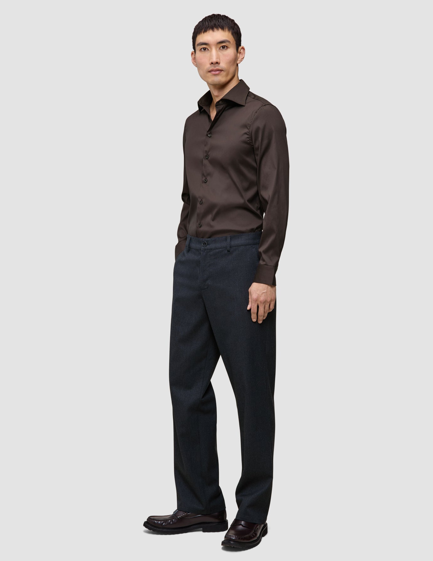 En mand iført en Elevated Shirt Slim i mørkebrun Pima-bomuld og antracitgrå bukser.