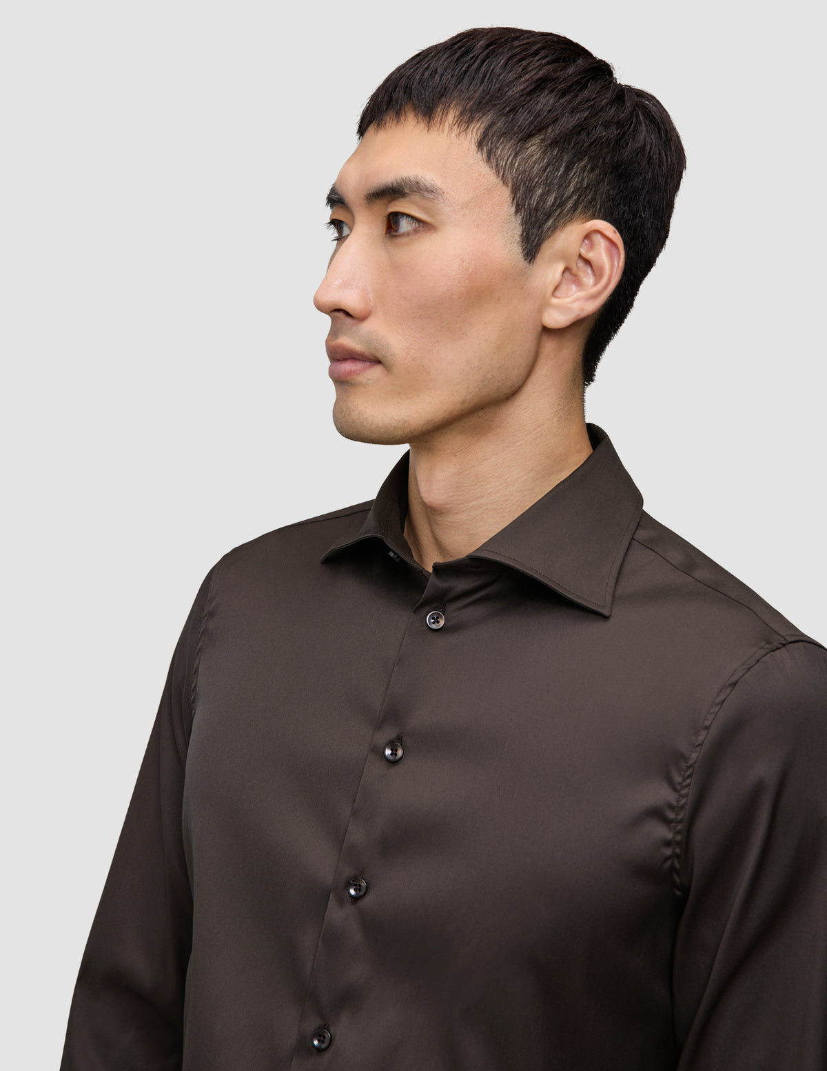 En mand iført en mørkebrun Elevated Shirt Slim-skjorte med knapper.