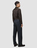 En person set bagfra, iført en mørkebrun Elevated Shirt Slim, antracitgrå bukser og mørke loafers.