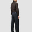 En person set bagfra, iført en mørkebrun Elevated Shirt Slim, antracitgrå bukser og mørke loafers.