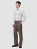 En mand iført en hvid Elevated Shirt White Slim og brune bukser står med den ene hånd i lommen.