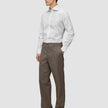 En mand iført en hvid Elevated Shirt White Slim og brune bukser står med den ene hånd i lommen.