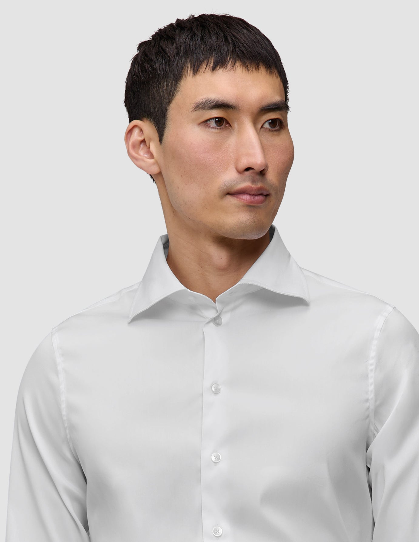 Mand iført en Elevated Shirt White Slim, en hvid skjorte med knapper og spredt krave.