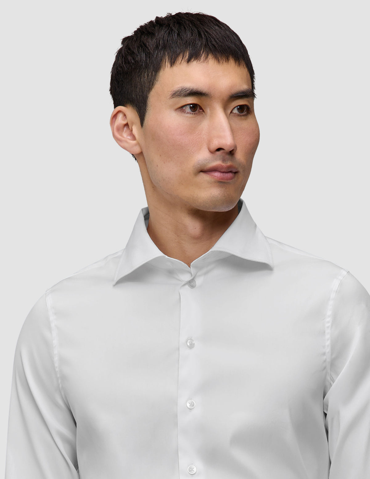 Mand iført en Elevated Shirt White Slim, en hvid skjorte med knapper og spredt krave.