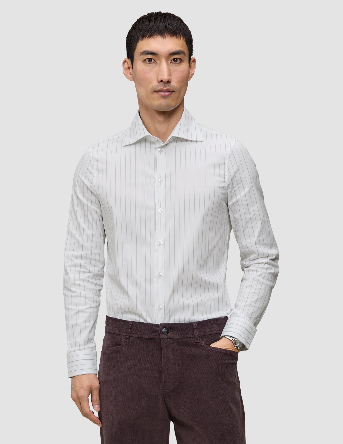 En mand iført en Elevated Shirt Slim Light Grey Striped, der er fremstillet af lysegråt stof med tynde lodrette striber.