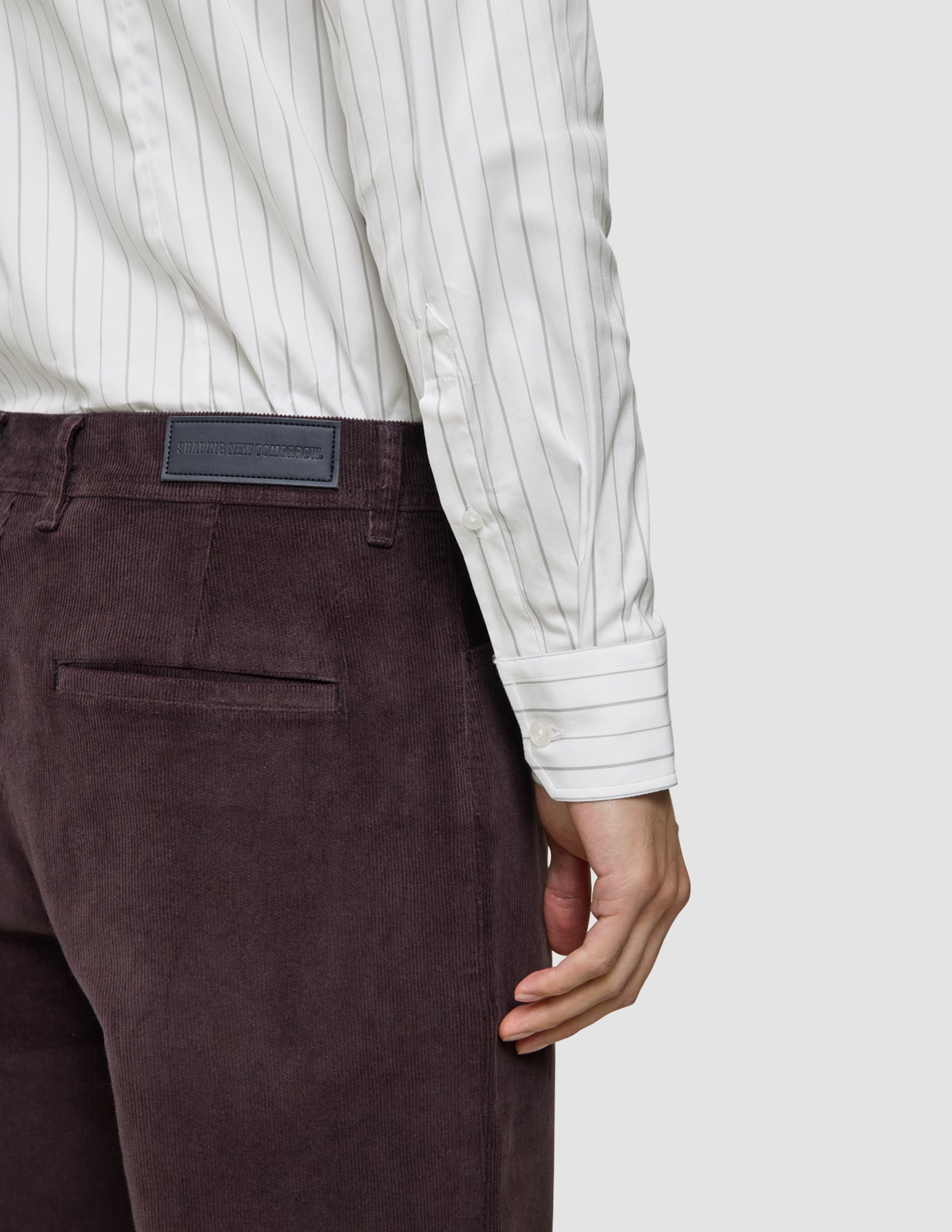 En person iført en Elevated Shirt Slim i lysegrå striber og mørkebrune fløjlsbukser.
