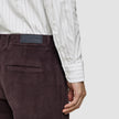 En person iført en Elevated Shirt Slim i lysegrå striber og mørkebrune fløjlsbukser.