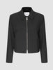 Essential Short Zip Jacket Black, en minimalistisk sort jakke med en sølvfarvet lynlås i fuld længde foran.