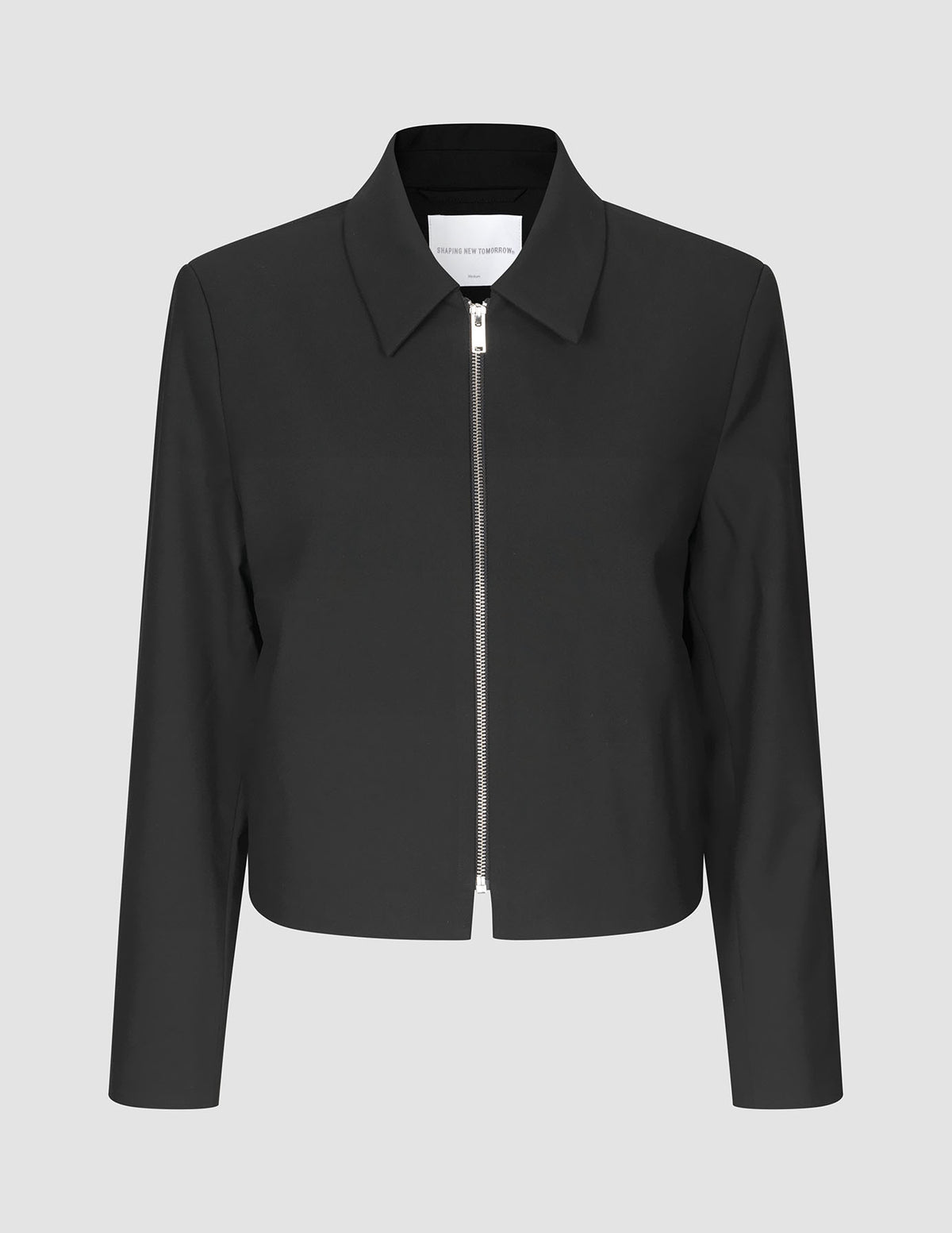 Essential Short Zip Jacket Black, en minimalistisk sort jakke med en sølvfarvet lynlås i fuld længde foran.
