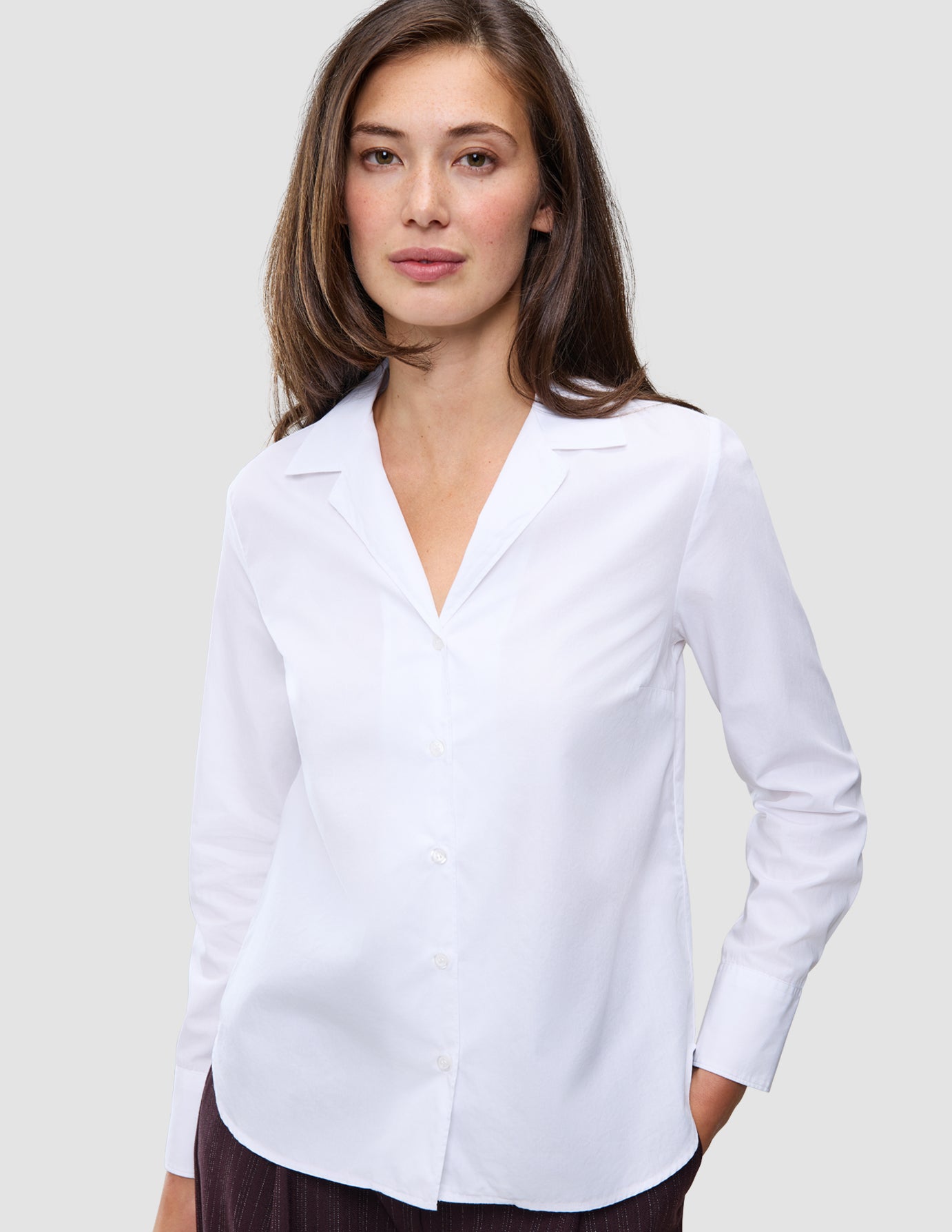 Kvinde iført en Madison Shirt White, en hvid skjorte med knapper og en krave med udskæring.