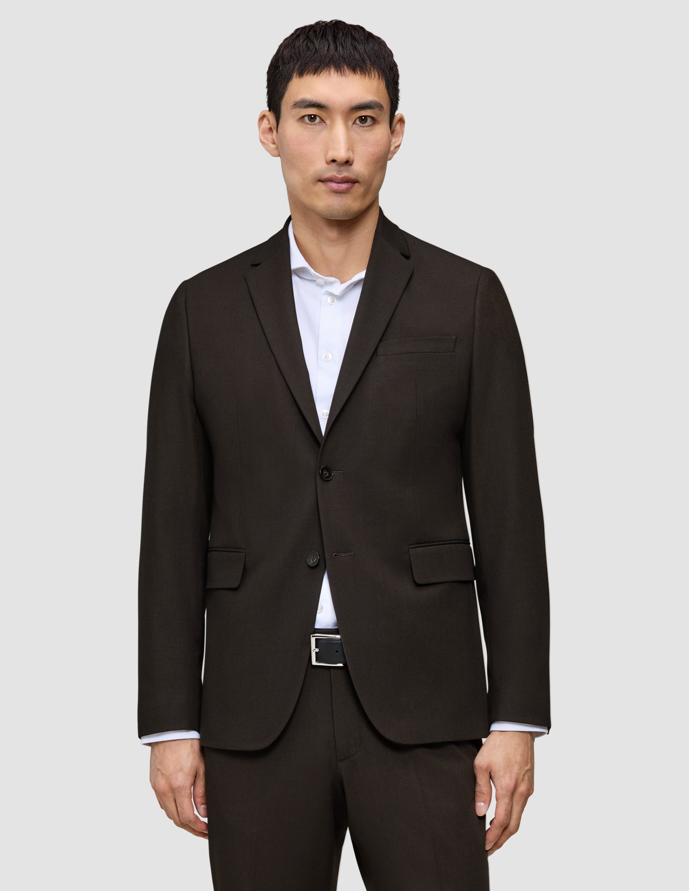 En mand iført en Motion Blazer Regular Cognac i mørkebrun over en hvid skjorte med knapper.