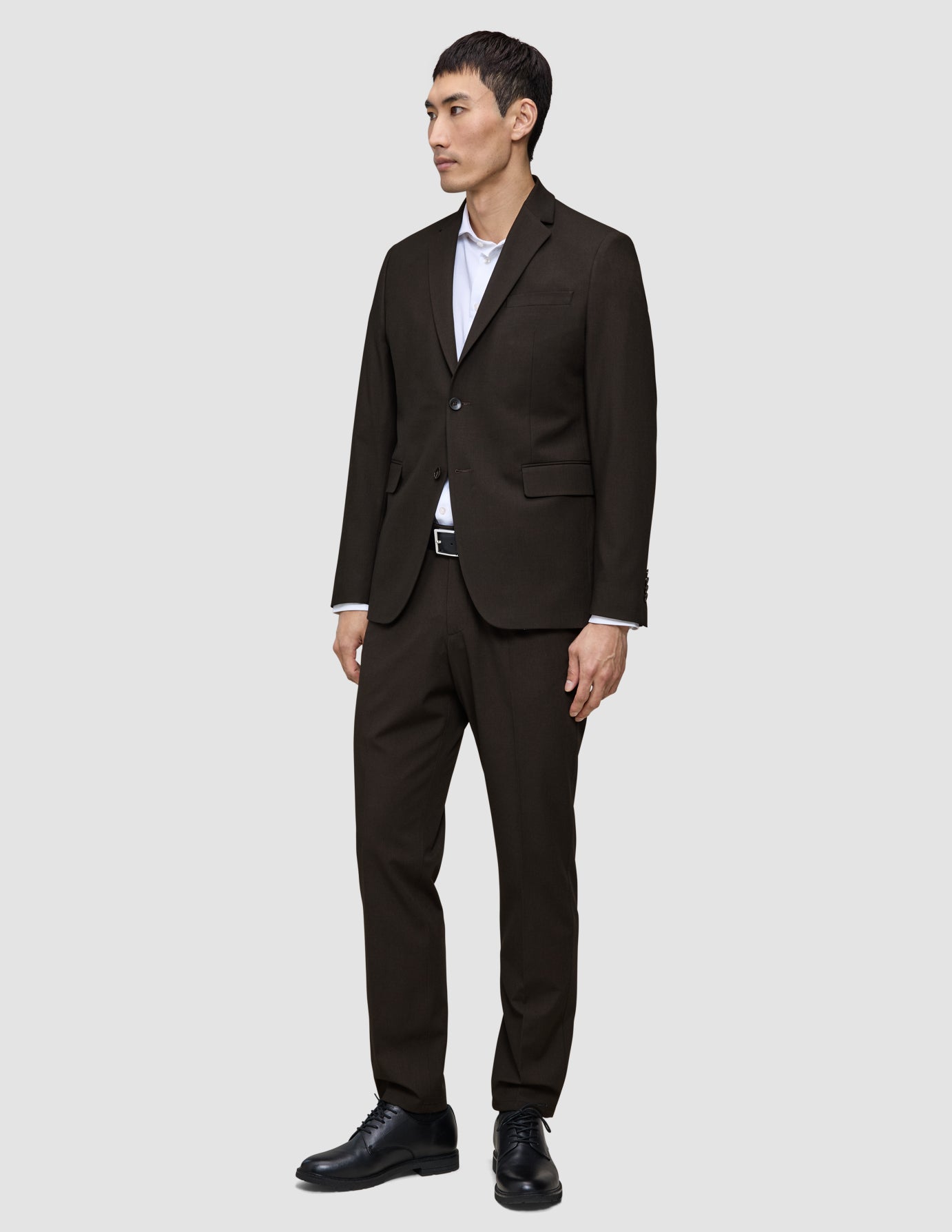 En mand iført en Motion Blazer Regular i farven Cognac, en hvid skjorte og sorte herresko.