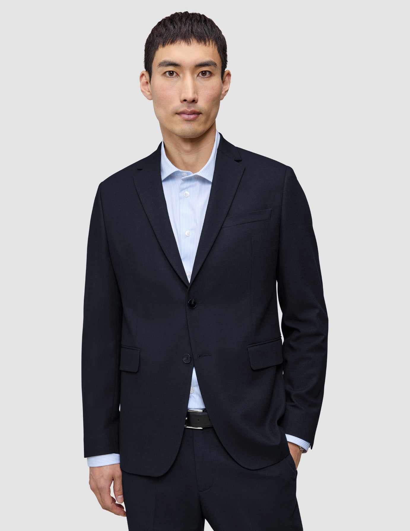 En mand bærer en Motion Blazer Regular i farven Midnight Blue over en lyseblå skjorte med knapper, hvilket fremhæver det rene danske design.