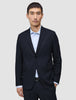 En mand bærer en Motion Blazer Regular i farven Midnight Blue over en lyseblå skjorte med knapper, hvilket fremhæver det rene danske design.