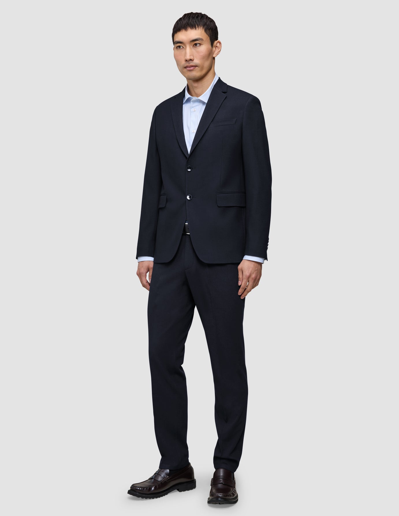 En mand iført en Motion Blazer Regular i farven Midnight Blue, en lyseblå skjorte og loafers – et perfekt eksempel på klassisk dansk design.