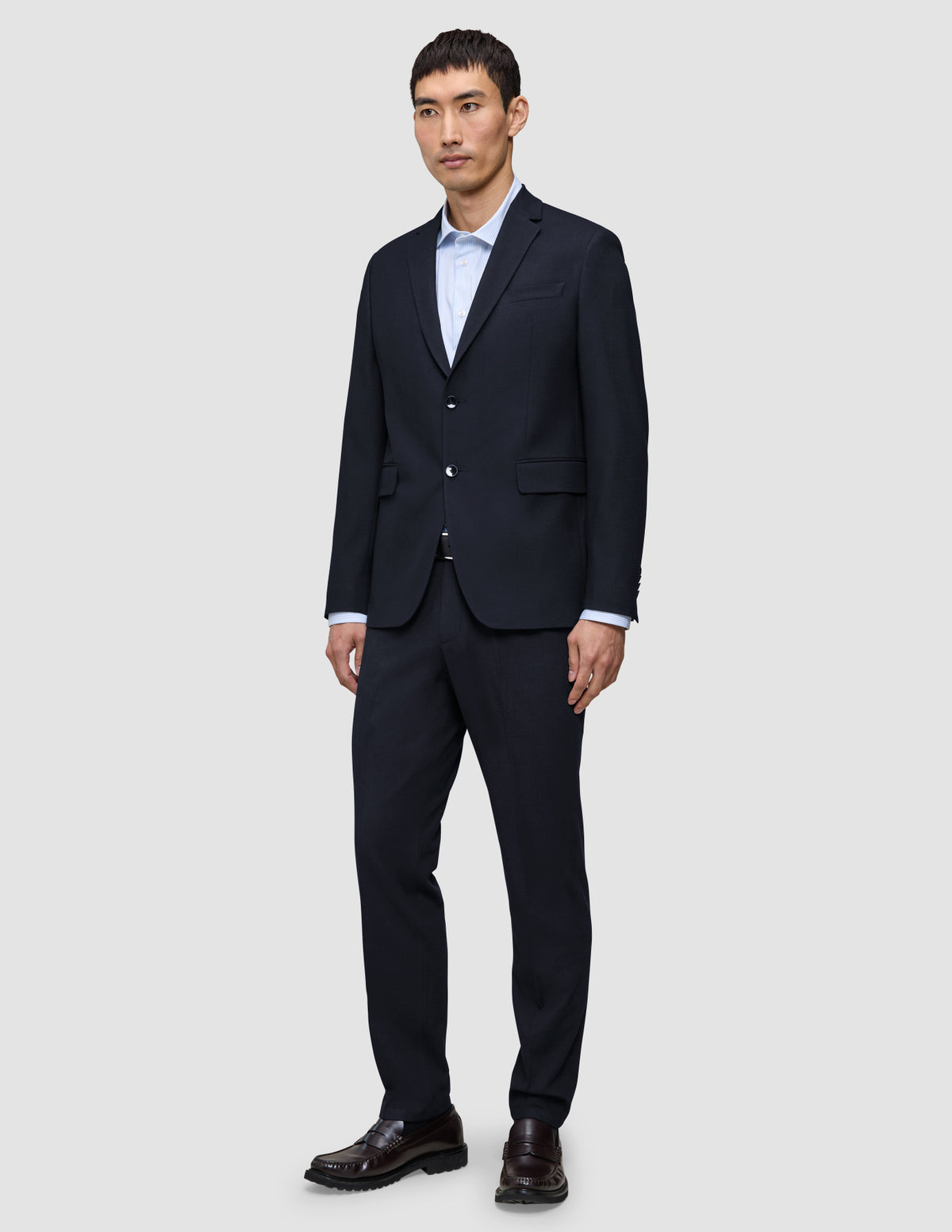En mand iført en Motion Blazer Regular i farven Midnight Blue, en lyseblå skjorte og loafers – et perfekt eksempel på klassisk dansk design.