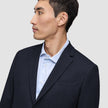 En mand iført en Motion Blazer Regular i farven Midnight Blue, som han har taget på over en lyseblå stribet skjorte.