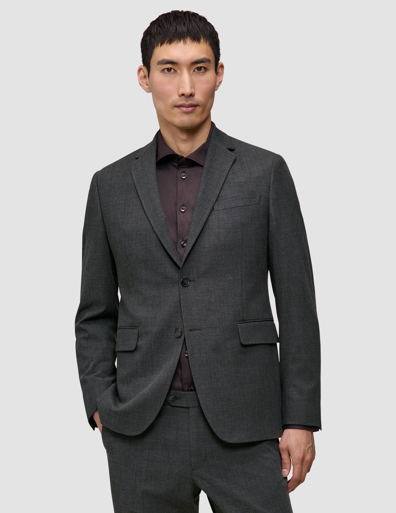 En mand iført en Motion Blazer Regular i farven Pepper Grey over en mørk skjorte med knapper.
