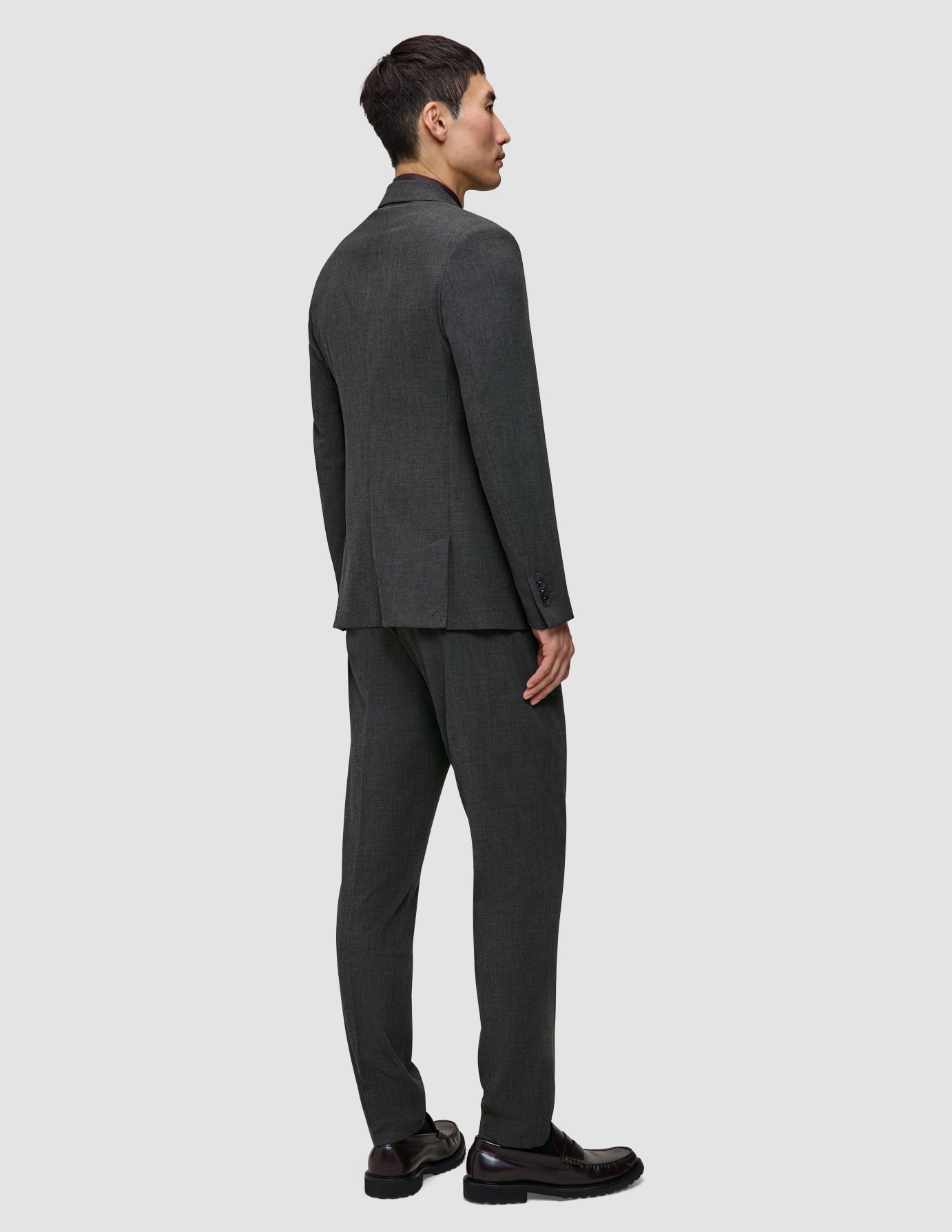 En mand iført en Motion Blazer Regular i farven Pepper Grey og mørke loafers, set bagfra.