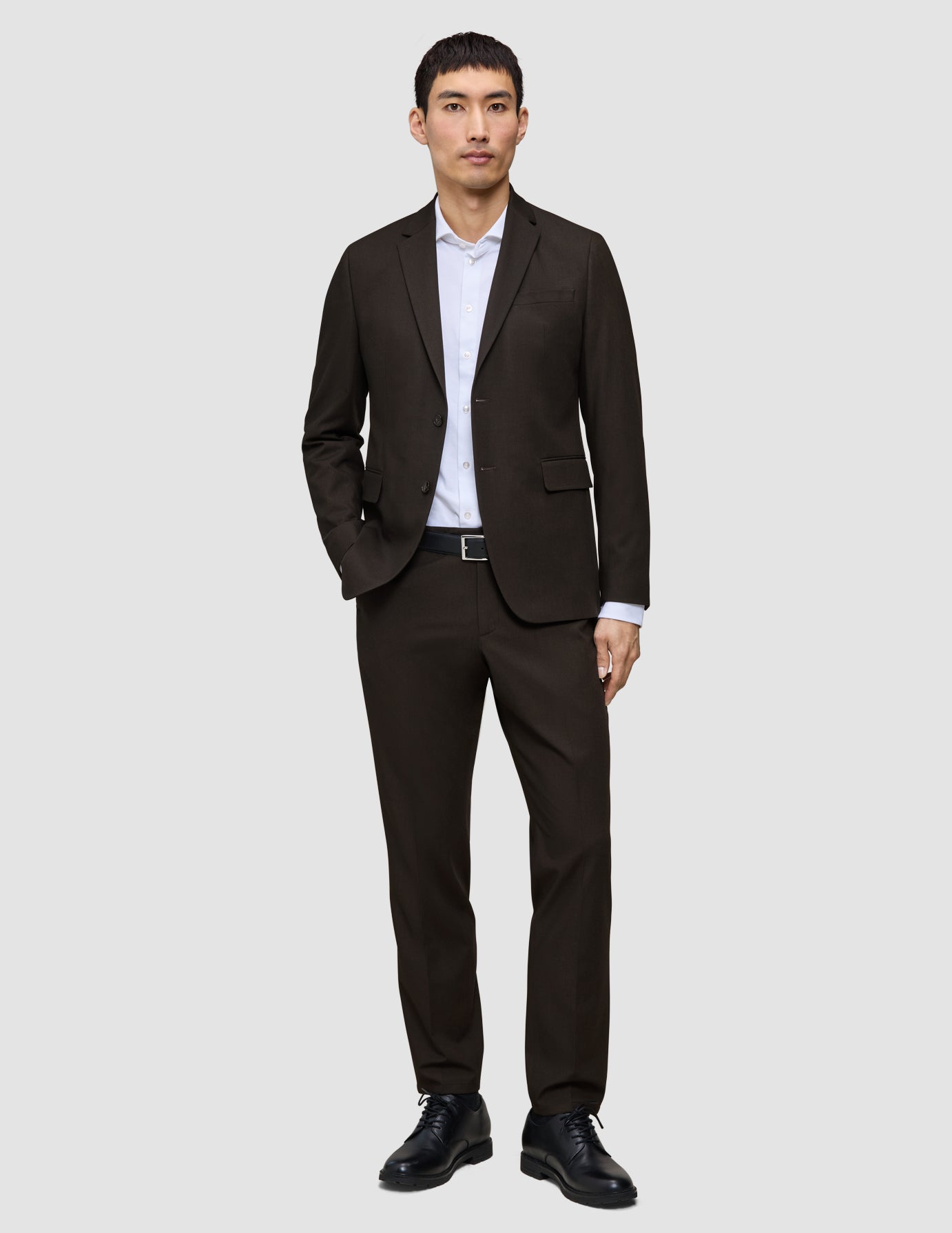 En mand iført en Motion Blazer Slim i farven Cognac, en hvid skjorte og sorte lædersko, der fremhæver det klassiske danske design.
