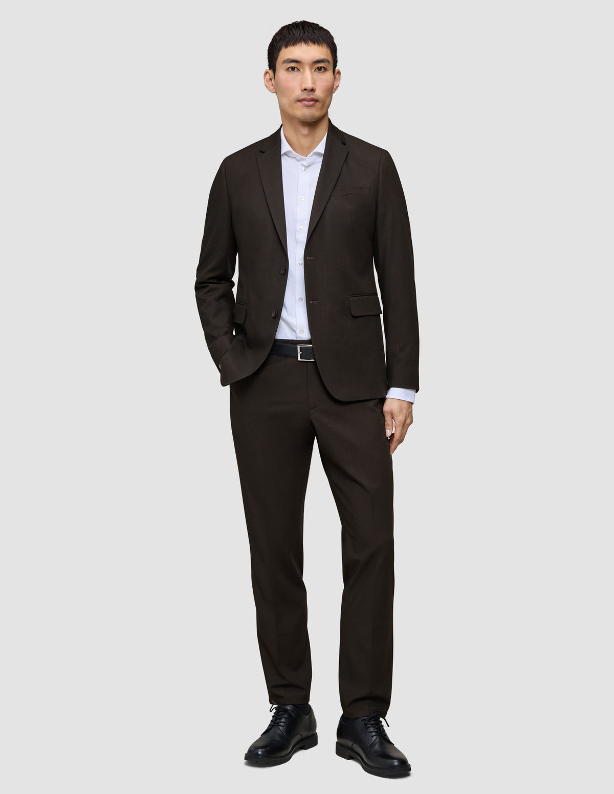 En mand iført en Motion Blazer Slim i farven Cognac, en hvid skjorte og sorte lædersko, der fremhæver det klassiske danske design.