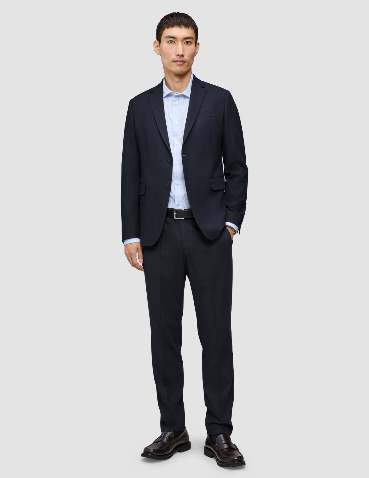 En mand iført en Motion Blazer Slim i farven Midnight Blue, en lyseblå skjorte og mørke læderloafers.