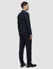 En mand set bagfra, iført en Motion Blazer Slim Midnight Blue-jakke og -bukser samt loafers.