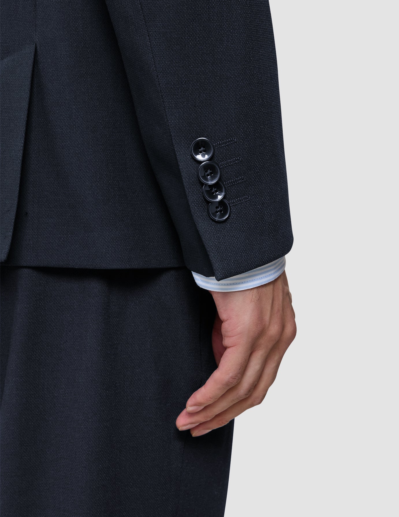 Nærbillede af et ærme fra en Motion Blazer Slim i farven Midnight Blue med fire manchetknapper og en stribet skjorte, der kan ses ved håndleddet.